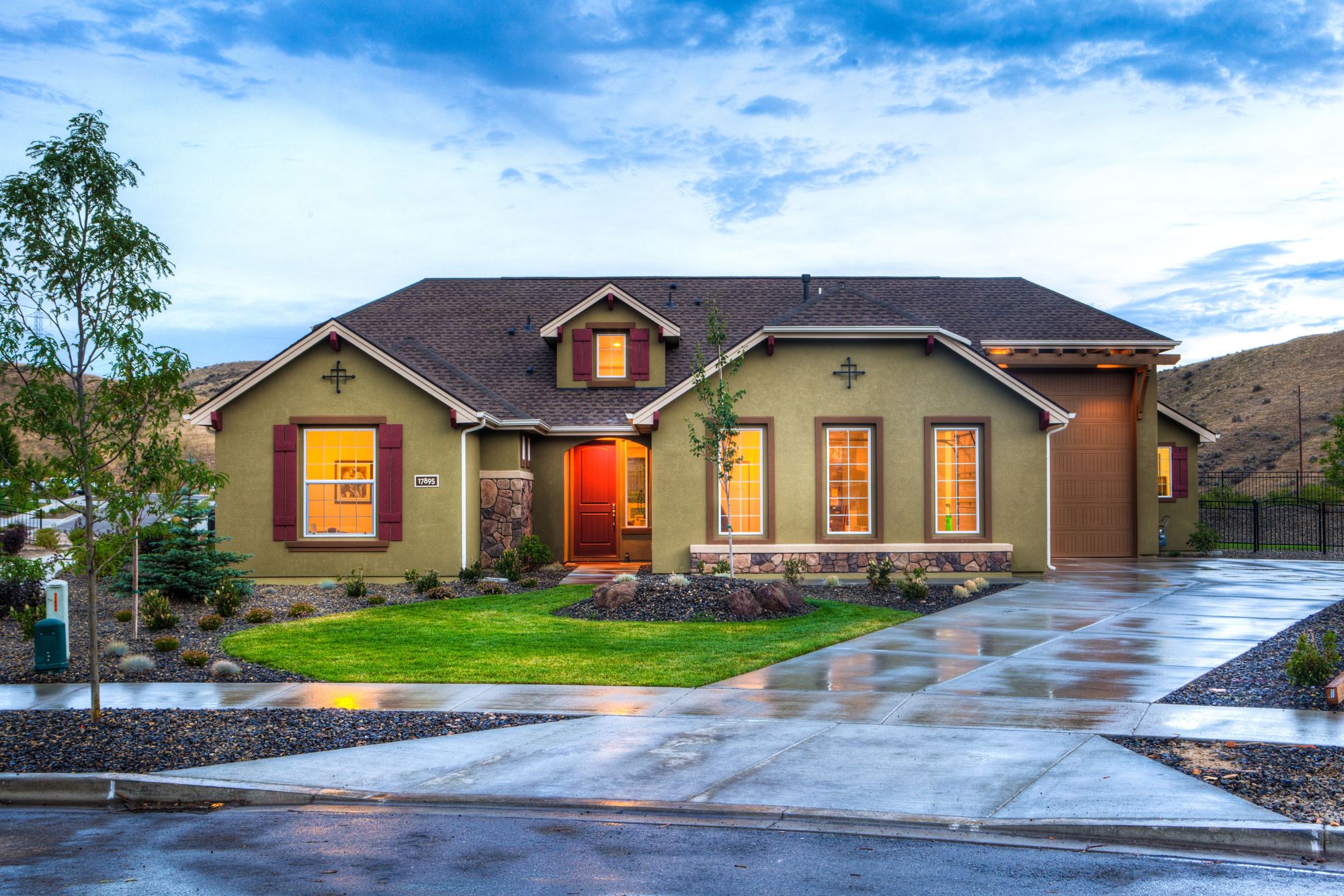 A single-story stone-and-siding home with a two-car garage and a green lawn