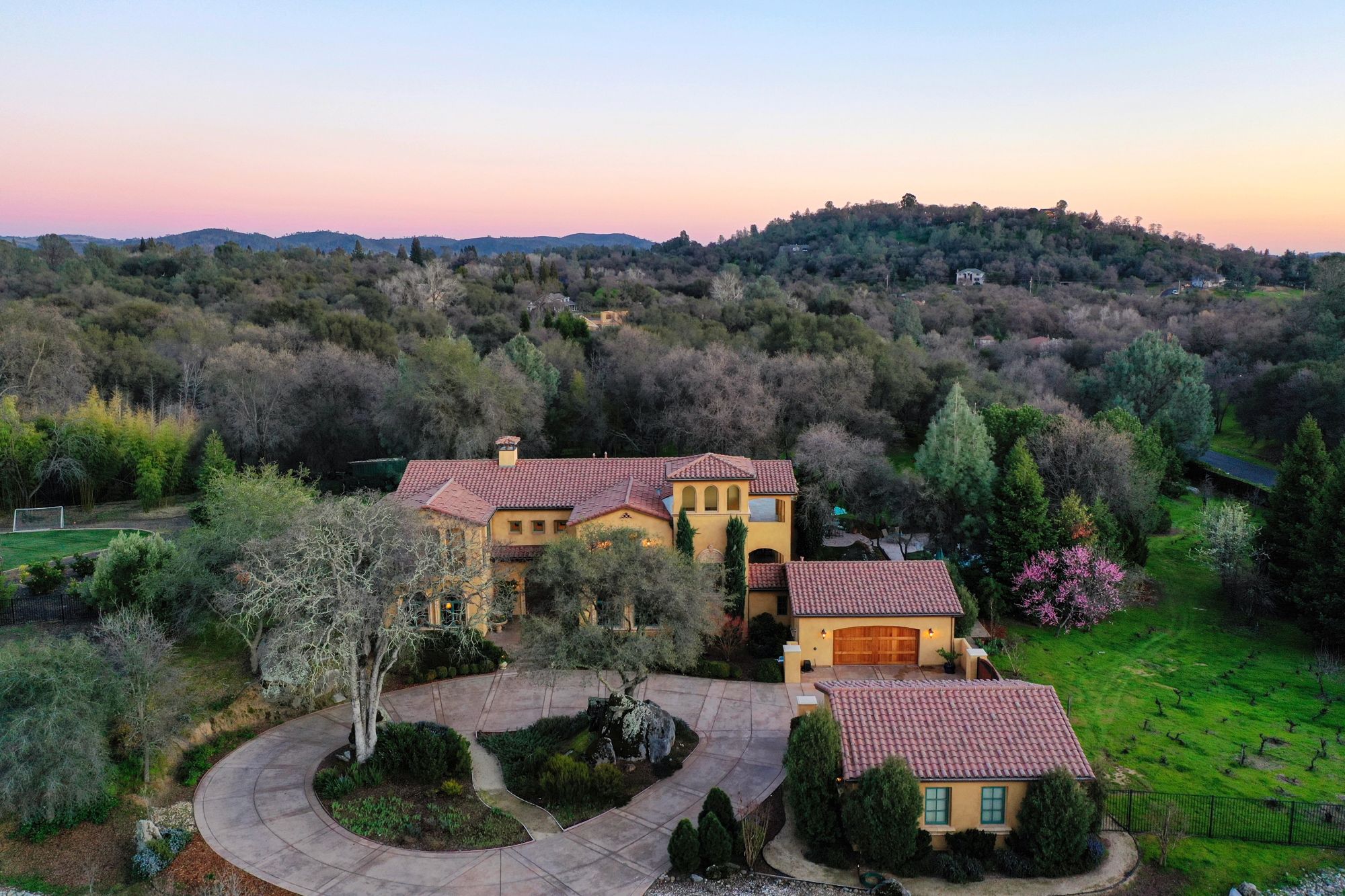 An aerial view of a Mediterranean-style estate with tile roofs among wooded hills
