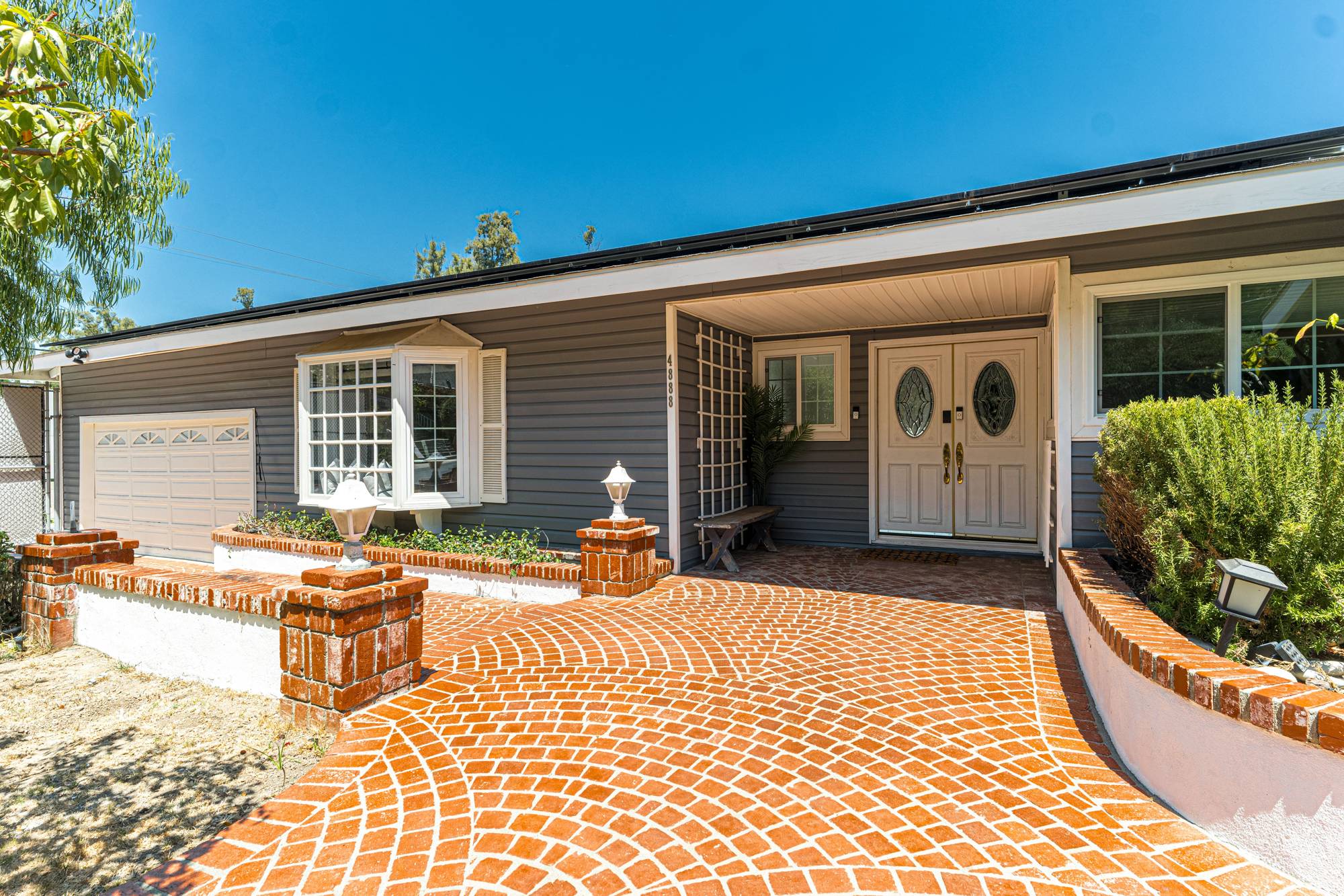 A single-story ranch home with a brick-paver driveway and a trimmed front lawn