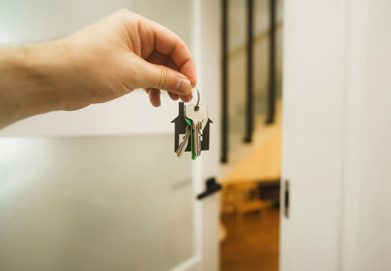 House keys resting on closing paperwork beside a welcome card