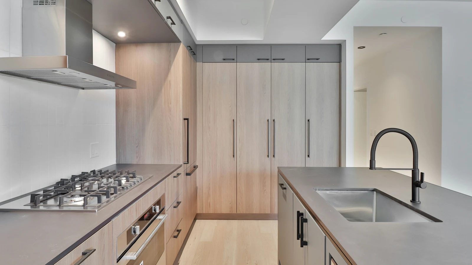 A sleek modern kitchen with wood cabinetry and a long stone counter