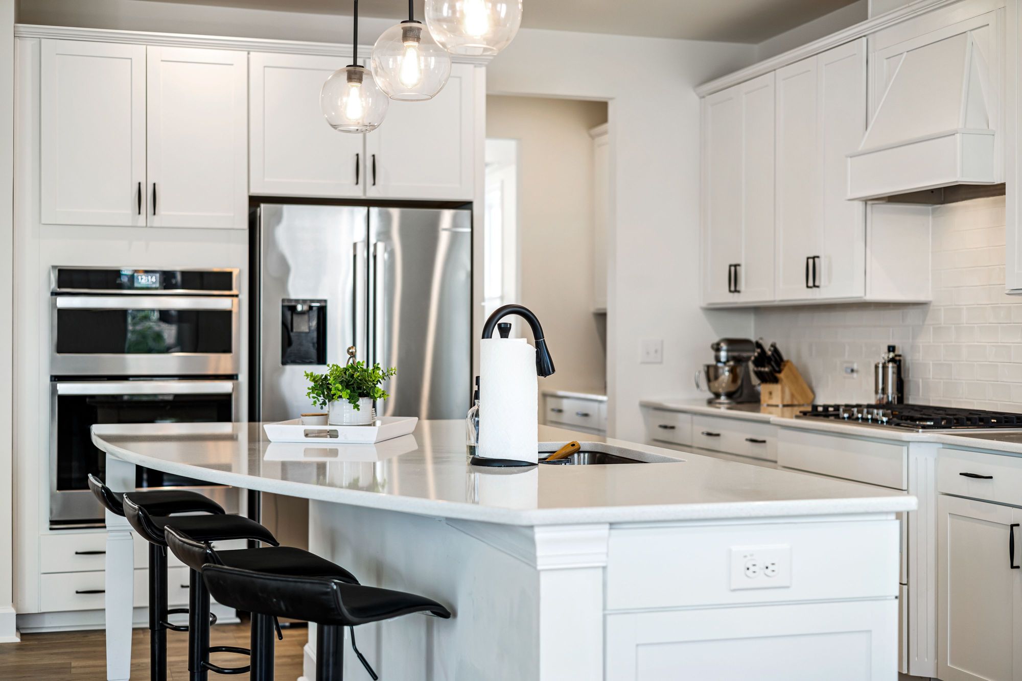 A white kitchen with a marble island and stainless appliances