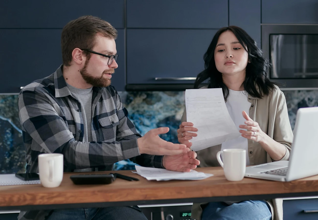 A couple at a kitchen table going through loan paperwork together
