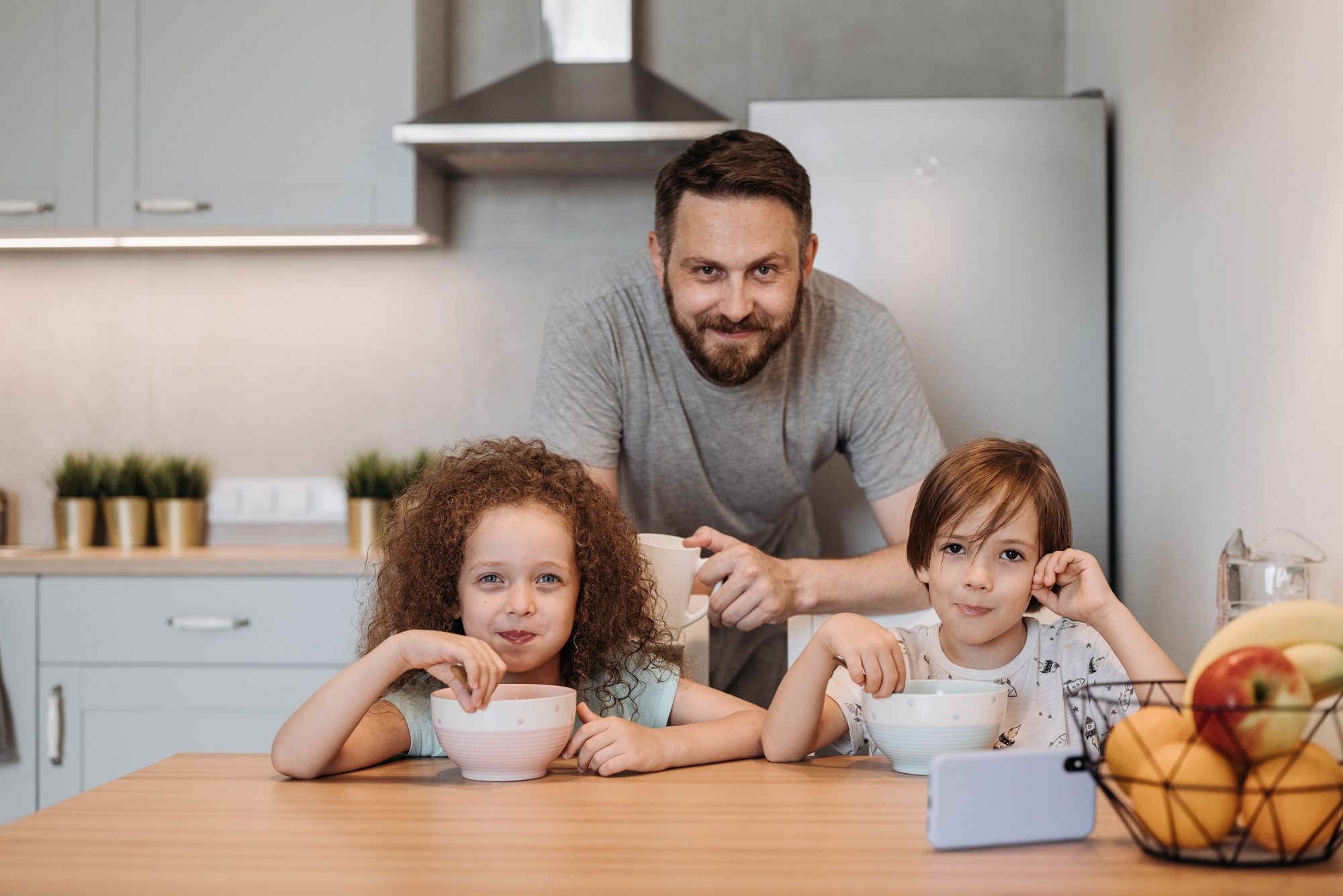 A father with his two children at a kitchen table at breakfast