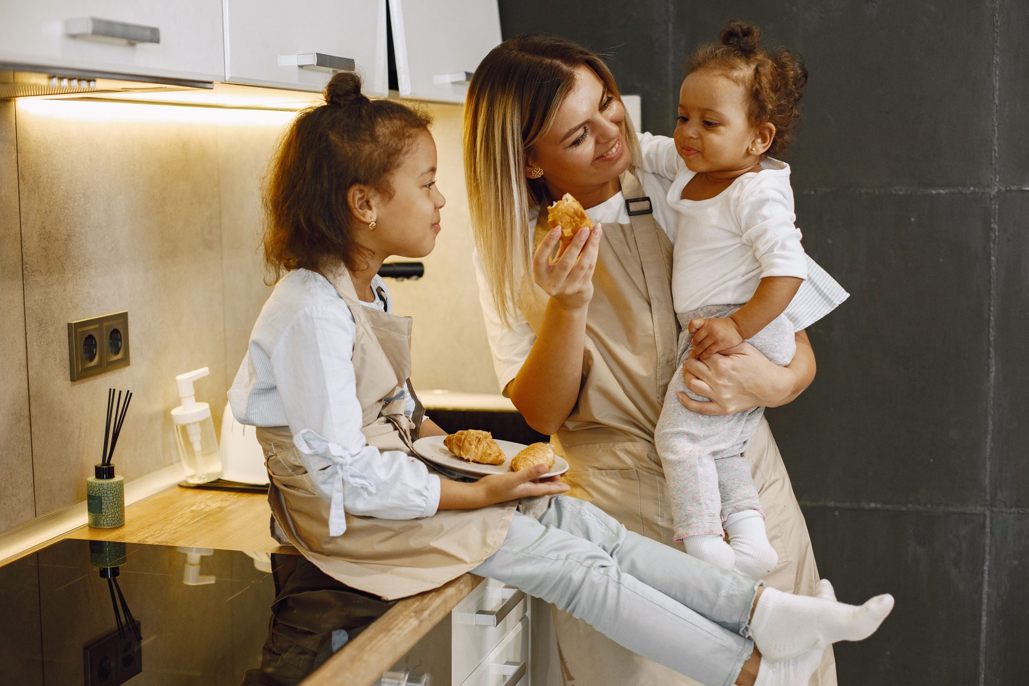 A mother sharing breakfast with her two young children at a kitchen counter