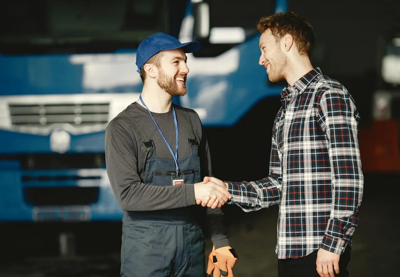 A homeowner shaking hands with a tradesperson in work overalls