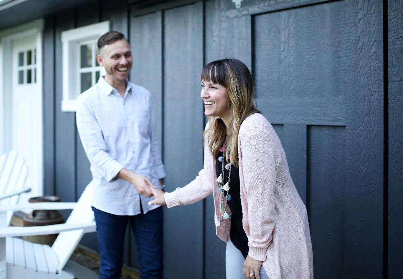 A smiling couple shaking hands at the front door of their new home
