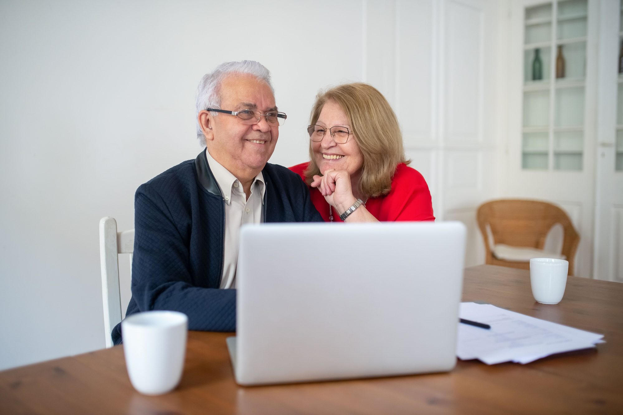 An older couple comparing plans on a laptop at their dining table