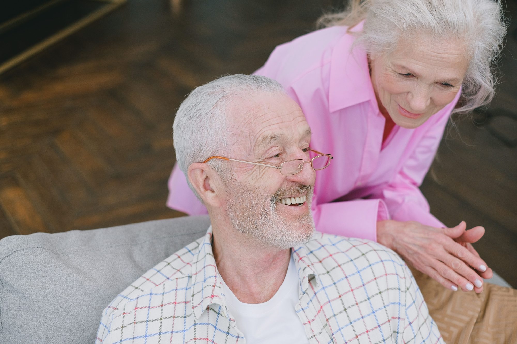 A smiling older couple sharing a laugh on the sofa at home