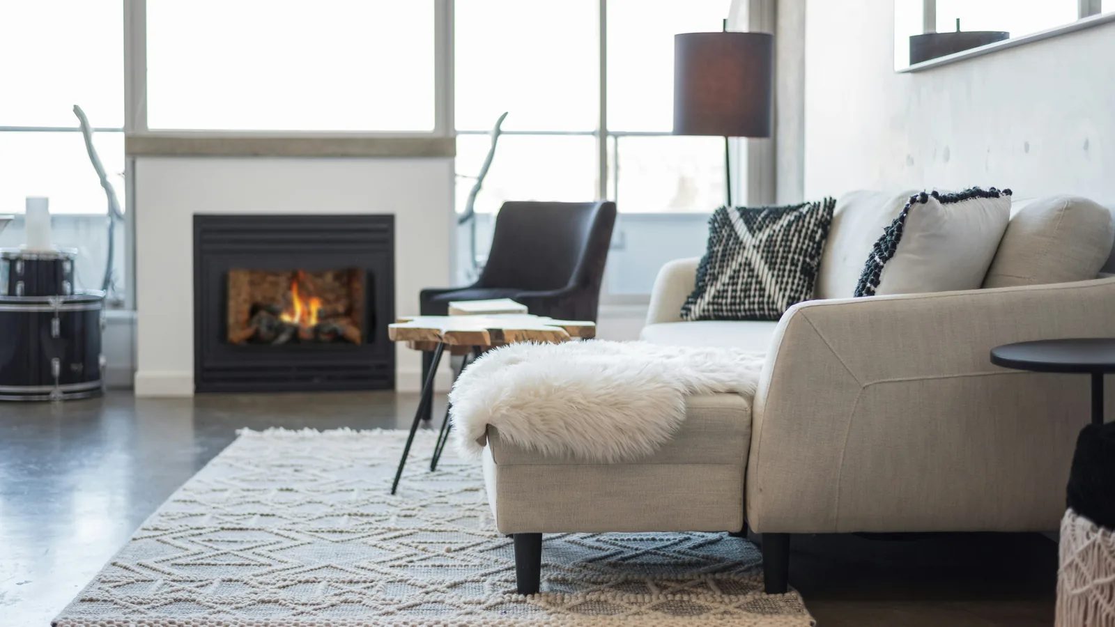 A modern living room with a stone fireplace and tall windows