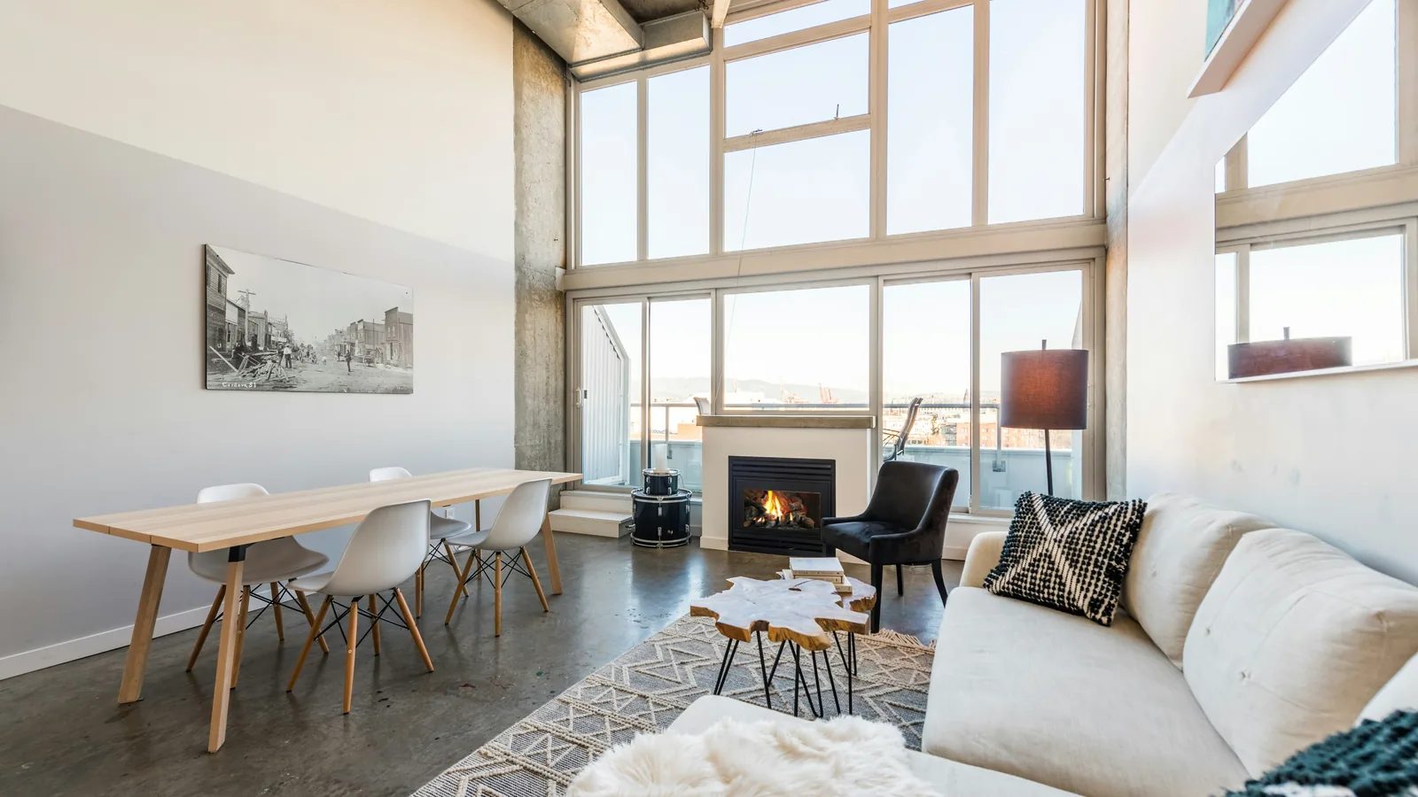A living room with a modern fireplace, a sofa and large windows onto a garden