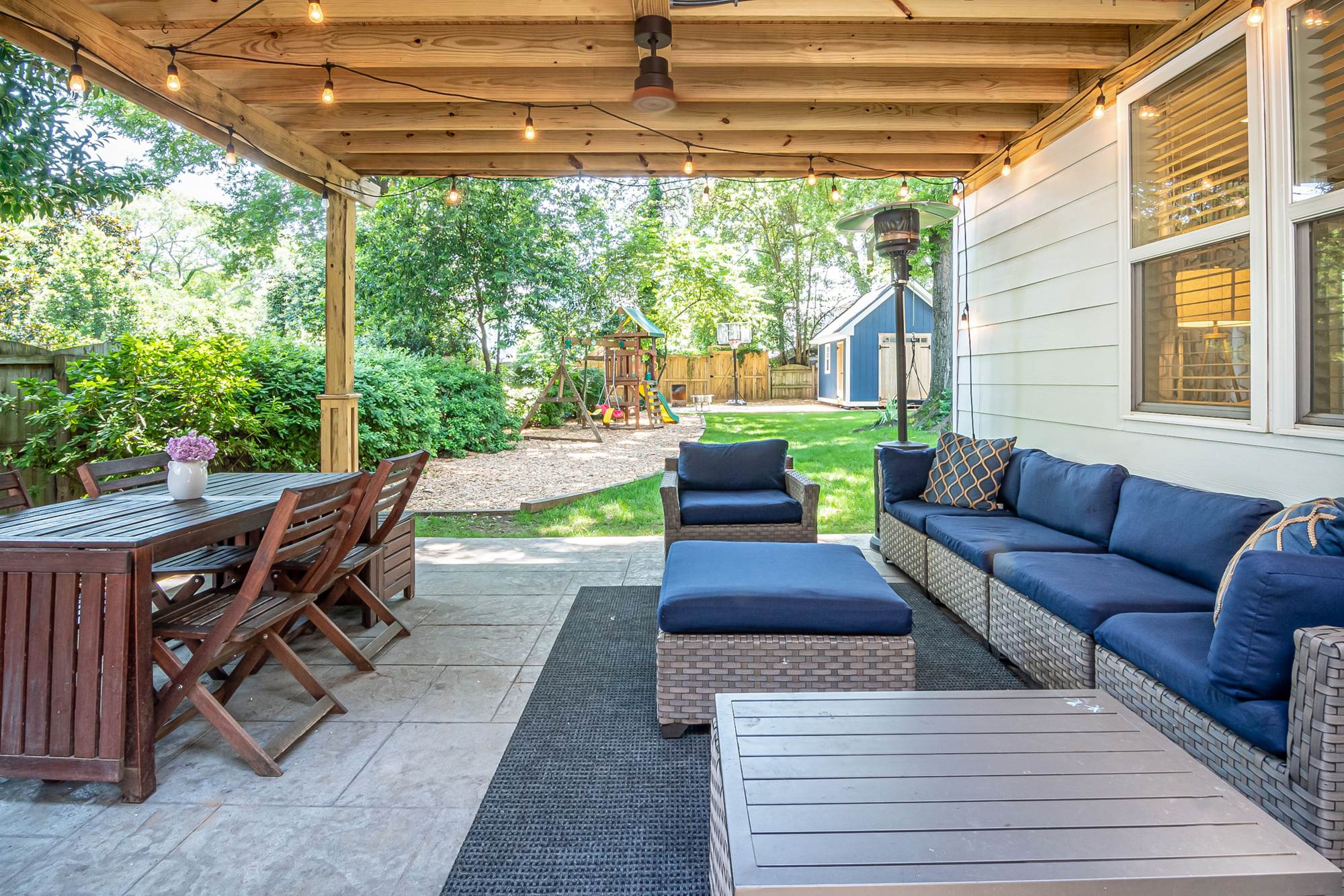 A covered back patio with a dining table and outdoor sofas