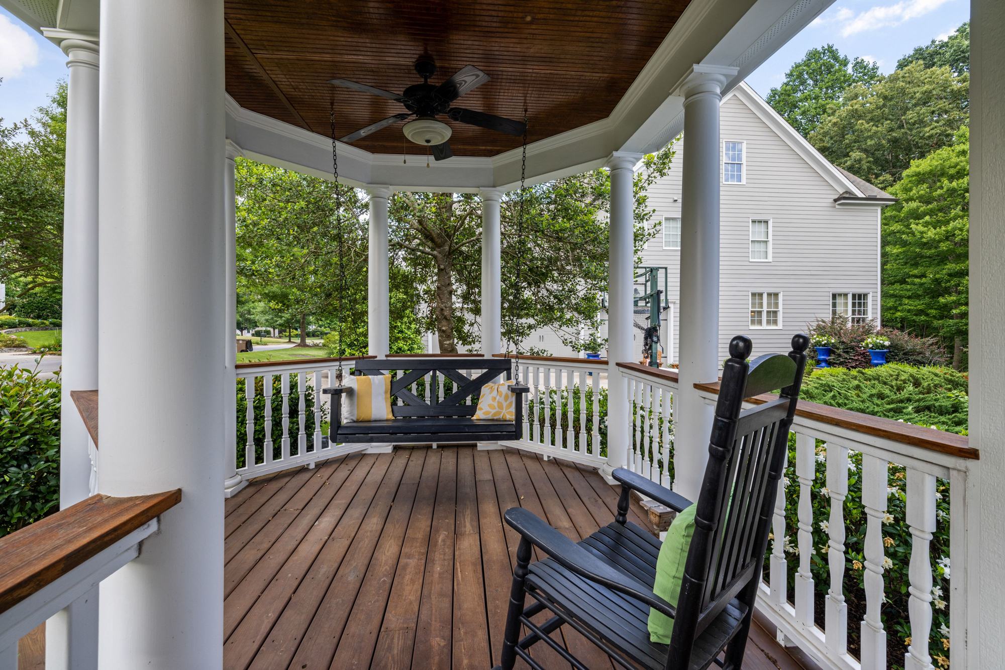A wraparound porch with a wood floor, painted ceiling and white columns