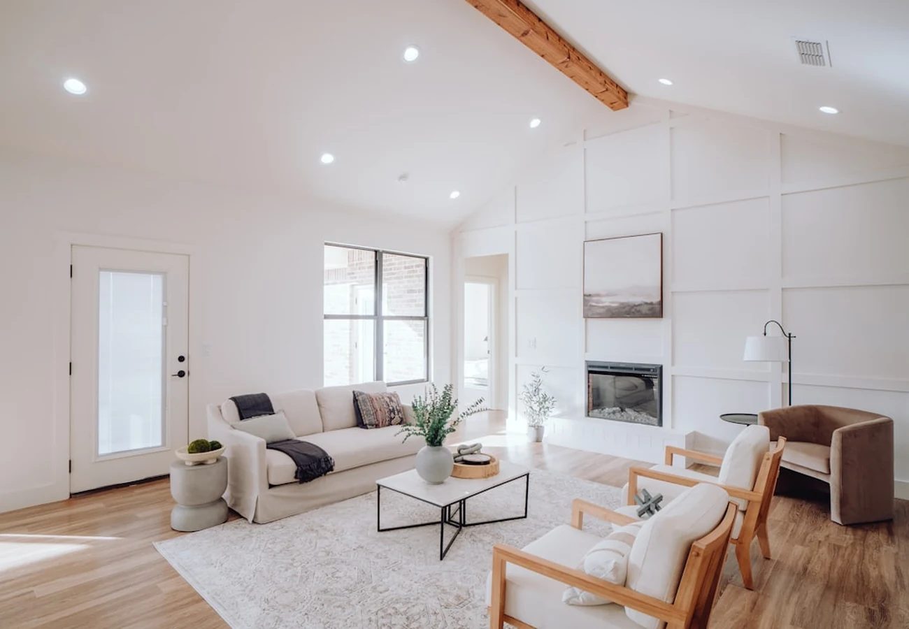 A bright, freshly staged living room with a white sofa and vaulted ceiling